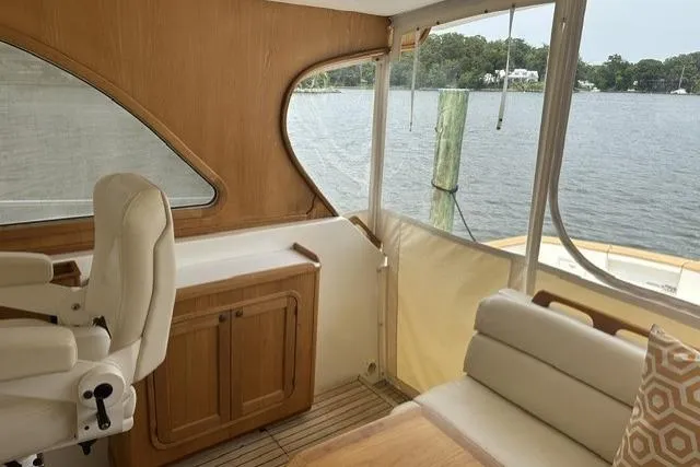 Slide: The Image of Interior of 2002 Legacy Express boat with wooden cabinetry and white seating by the water. - 12