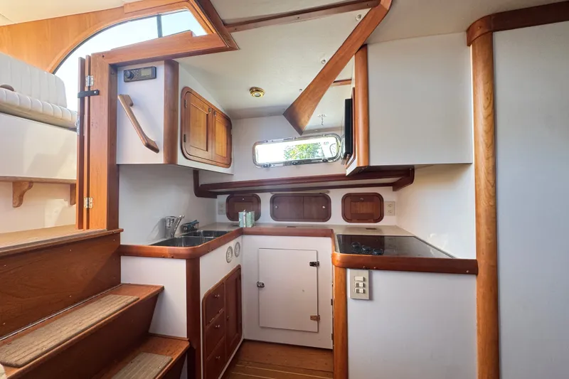 Slide: The Image of 2002 Legacy Express boat interior with wooden cabinetry, compact kitchen, and stairs. - 49