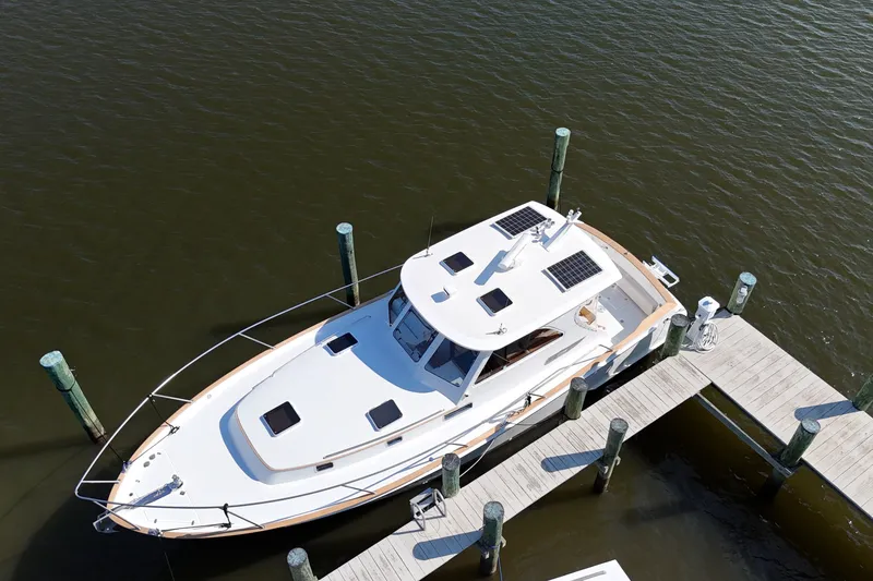 Slide: The Image of 2002 Legacy Express boat docked at marina, featuring solar panels on the roof. - 61