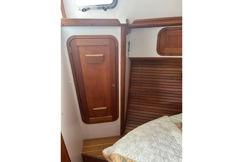 Slide: The Image of Interior of 2002 Legacy Express boat with wooden cabinetry and cozy bedding. - 22