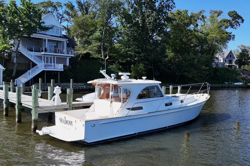 Slide: The Image of 2002 Legacy Express boat docked by waterfront homes, surrounded by lush greenery. - 71