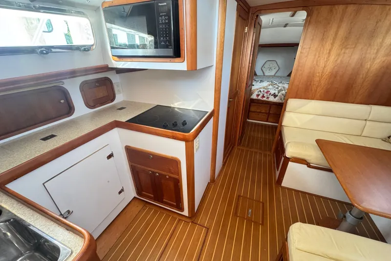 Slide: The Image of Cozy 2002 Legacy Express yacht interior with kitchen, dining area, and sleeping quarters. - 52