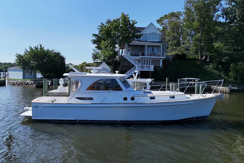 Slide: The Image of 2002 Legacy Express boat docked by a waterfront house, surrounded by lush greenery. - 33