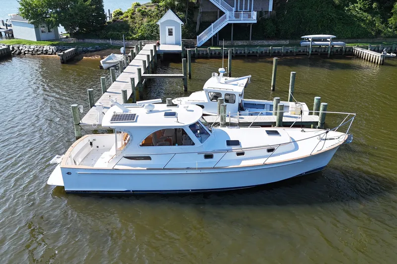 Slide: The Image of 2002 Legacy Express boat docked at a marina, surrounded by calm water. - 63