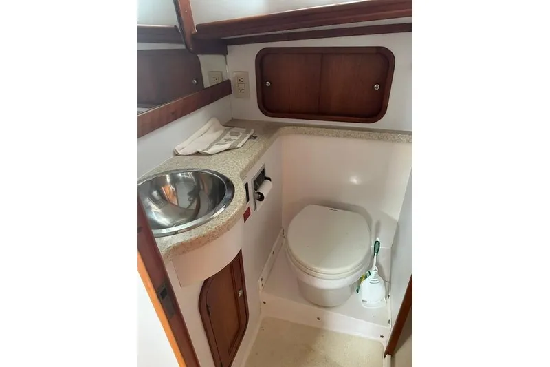 Slide: The Image of Compact boat bathroom with sink and toilet, featuring wooden accents, in a 2002 Legacy Express. - 25