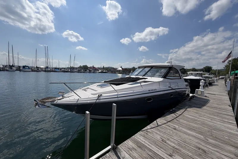 The Image of 2021 Regal 35 Sport Coupe docked at a marina under a partly cloudy sky. - 0