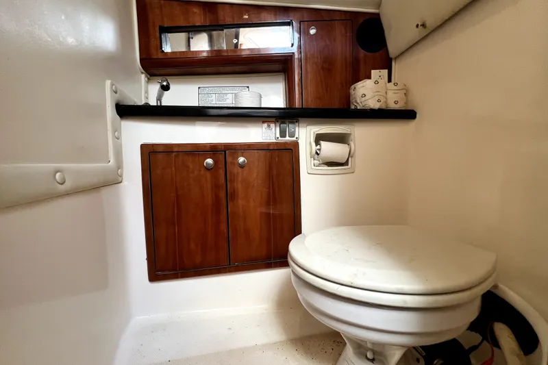 Slide: The Image of 2004 Century 3200 Walk-Around boat bathroom with wooden cabinets and compact toilet. - 105