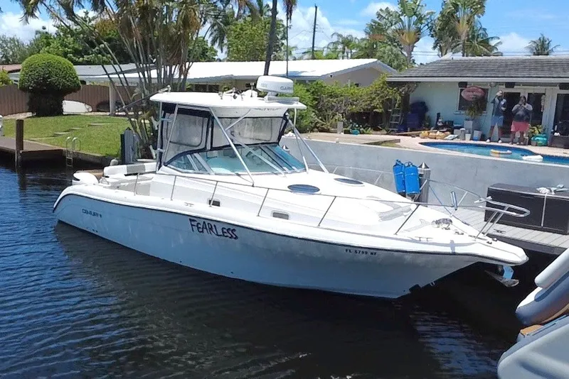 The Image of 2004 Century 3200 Walk-Around boat named "Fearless" docked by a waterfront home. - 0