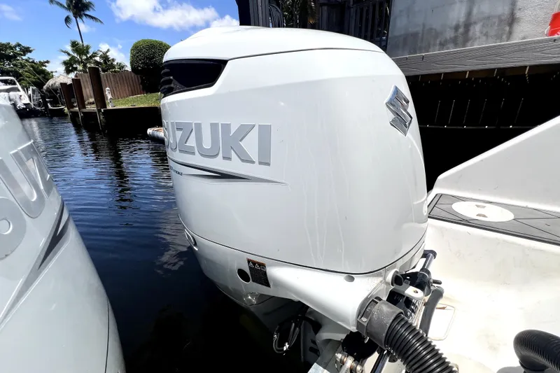 Slide: The Image of Suzuki outboard motor on a 2004 Century 3200 Walk-Around boat, docked by water. - 74