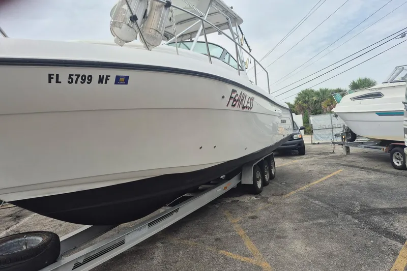 Slide: The Image of 2004 Century 3200 Walk-Around boat on trailer, labeled "Fearless," parked in a lot. - 8