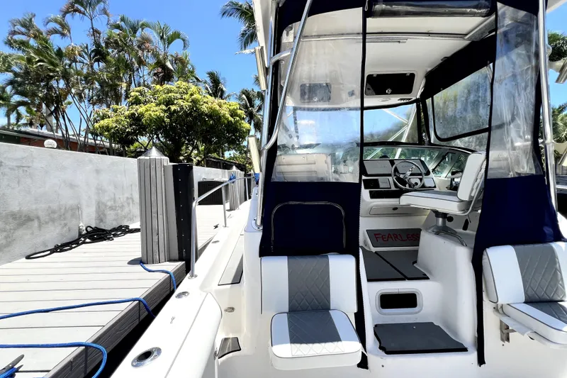Slide: The Image of 2004 Century 3200 Walk-Around boat docked, featuring helm and seating area under clear canopy. - 28