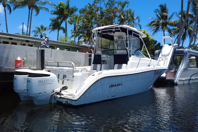 Slide: The Image of 2004 Century 3200 Walk-Around boat docked with Suzuki engines, surrounded by palm trees. - 5