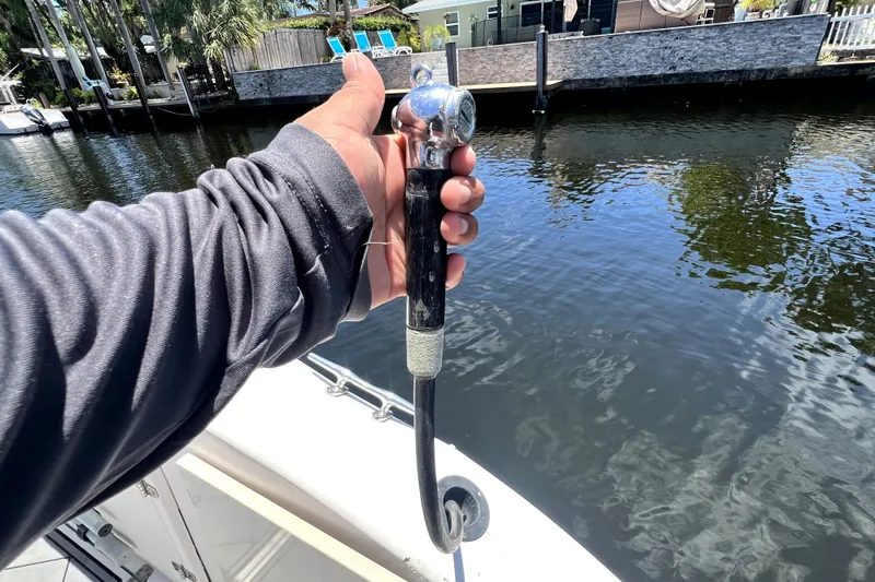 Slide: The Image of Hand holding a boat fuel nozzle on a 2004 Century 3200 Walk-Around near a dock. - 56