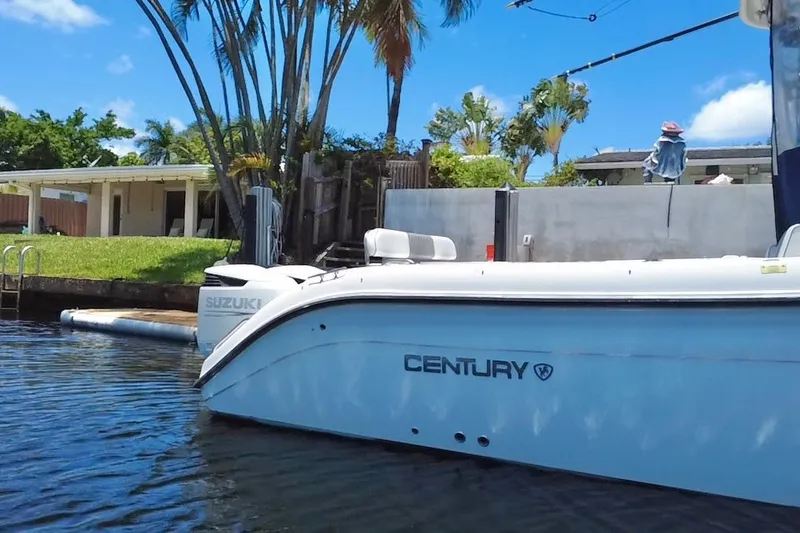 Slide: The Image of 2004 Century 3200 Walk-Around boat docked near a waterfront home with lush greenery. - 4