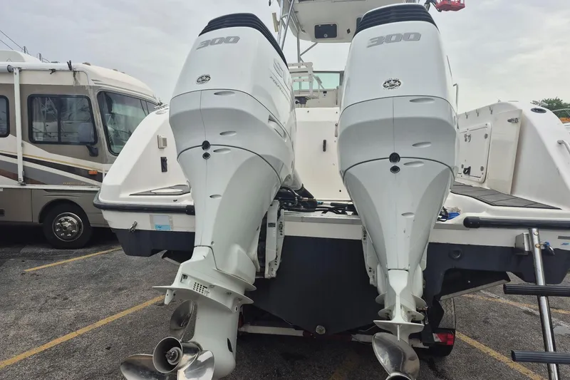 Slide: The Image of Twin outboard engines on a 2004 Century 3200 Walk-Around boat in a parking lot. - 4