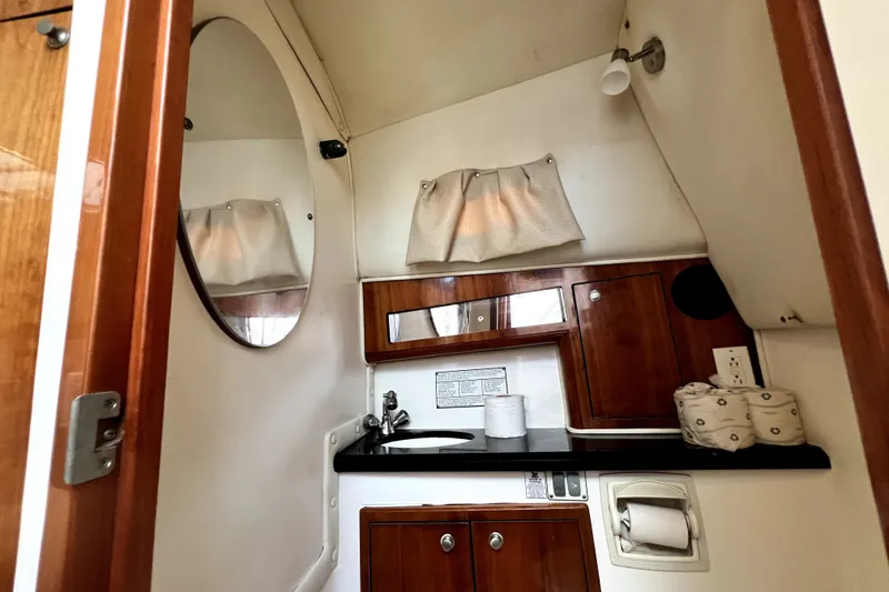 Slide: The Image of 2004 Century 3200 Walk-Around boat bathroom with wood cabinets and mirror. - 108