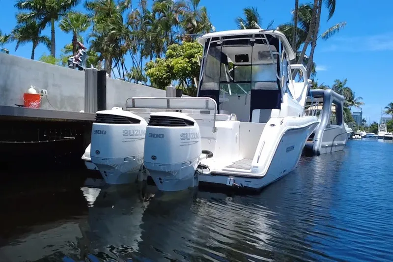 Slide: The Image of 2004 Century 3200 Walk-Around boat with twin Suzuki 300 engines docked by palm trees. - 7