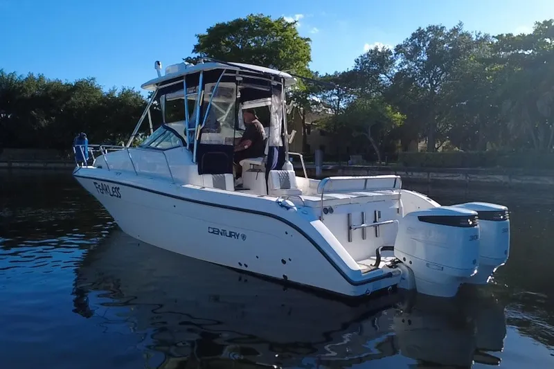 Slide: The Image of 2004 Century 3200 Walk-Around boat on calm water, featuring dual outboard engines. - 3