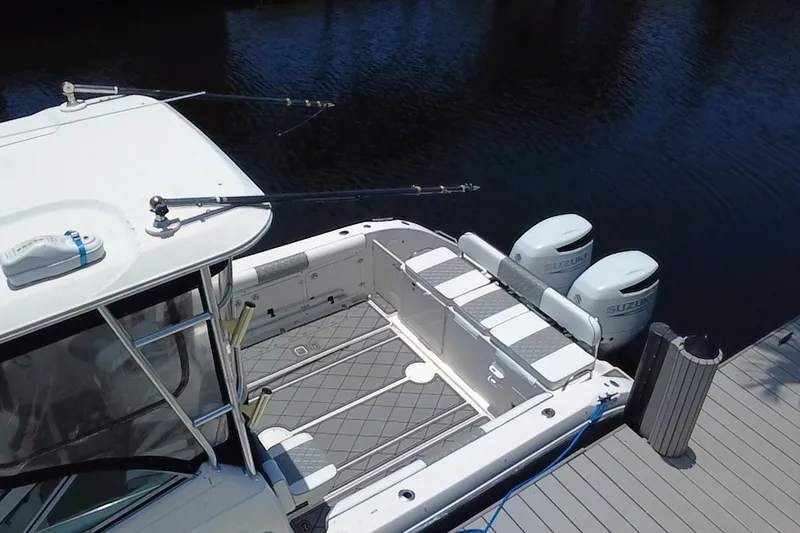 Slide: The Image of 2004 Century 3200 Walk-Around boat with dual Suzuki outboard motors docked by water. - 12