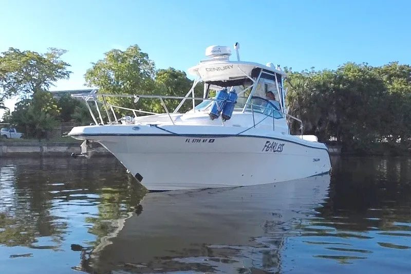 Slide: The Image of 2004 Century 3200 Walk-Around boat on calm water, surrounded by lush greenery. - 1
