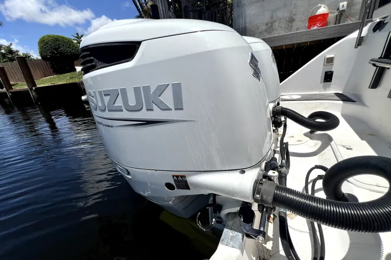 Slide: The Image of Suzuki outboard motor on a 2004 Century 3200 Walk-Around boat, docked by water. - 78