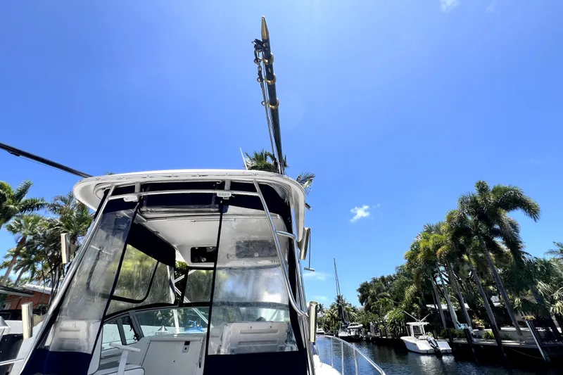 Slide: The Image of 2004 Century 3200 Walk-Around boat docked under clear blue sky with palm trees. - 83