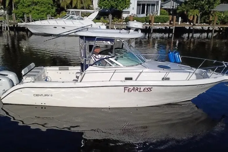 Slide: The Image of 2004 Century 3200 Walk-Around boat named "Fearless" docked on a calm waterfront. - 8