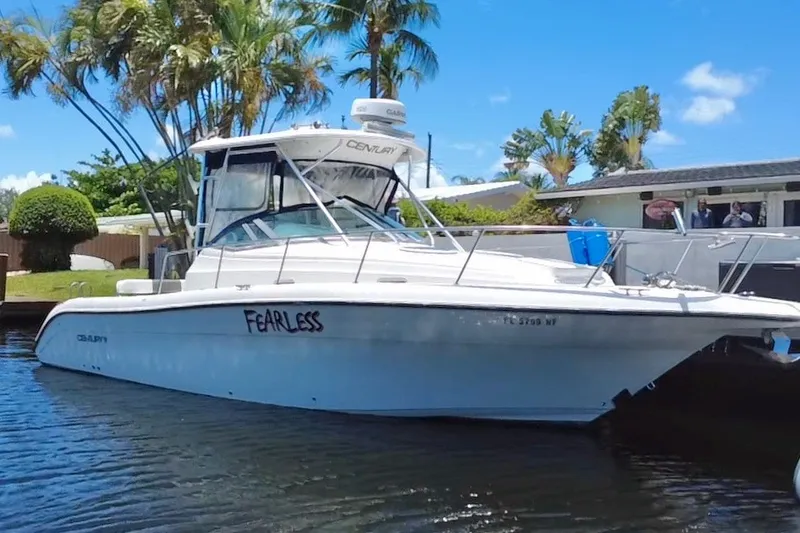 Slide: The Image of 2004 Century 3200 Walk-Around boat named "Fearless" docked by palm trees. - 1