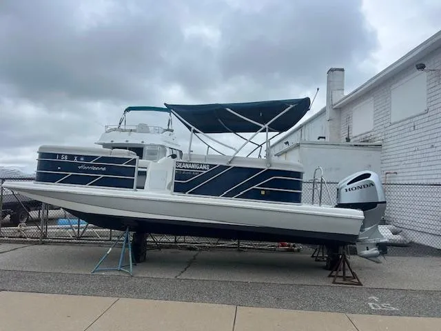 The Image of 2021 Hurricane FunDeck 236SB OB boat with Honda outboard motor, docked near a white building. - 1