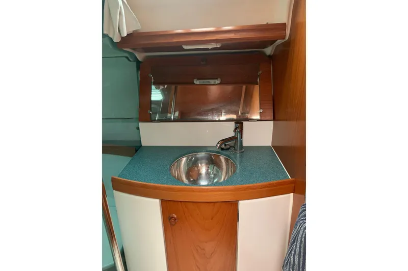 Slide: The Image of Interior of 2000 Jeanneau Sun Odyssey 37 yacht, featuring a compact sink and wooden cabinetry. - 37