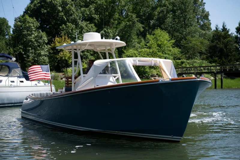 Slide: The Image of 2021 Hinckley Talaria 29C boat cruising on a serene waterway with lush greenery. - 3