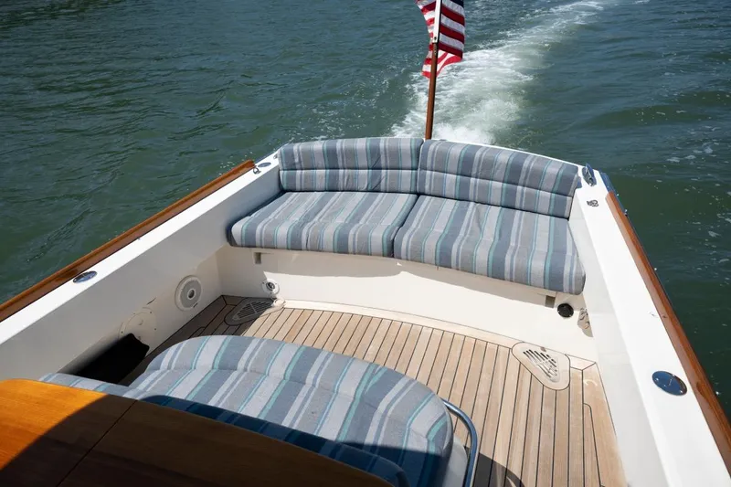 Slide: The Image of 2021 Hinckley Talaria 29C boat with striped seating and American flag on water. - 15