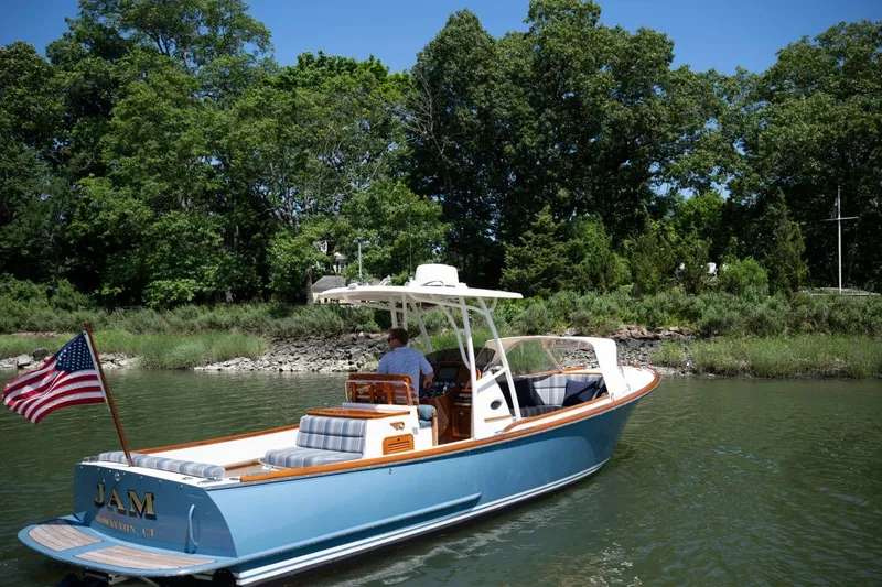 Slide: The Image of 2021 Hinckley Talaria 29C cruising on a serene river with lush green trees. - 2