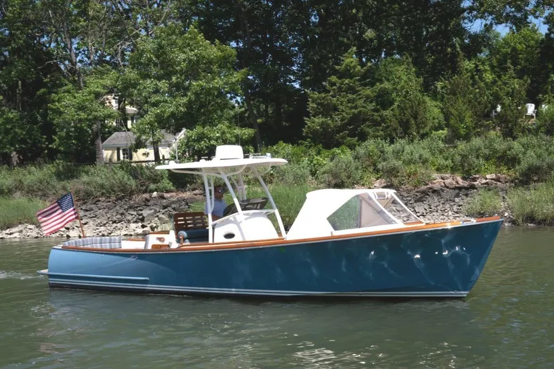 Slide: The Image of 2021 Hinckley Talaria 29C boat cruising on a river with lush greenery background. - 1