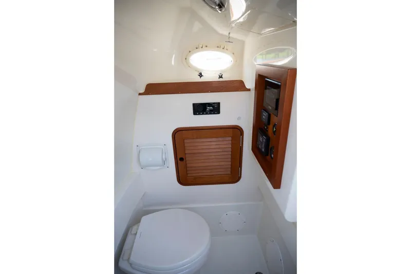 Slide: The Image of 2021 Hinckley Talaria 29C boat interior with compact bathroom and wooden accents. - 19
