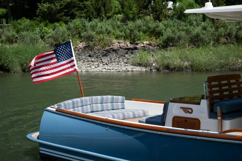 Slide: The Image of 2021 Hinckley Talaria 29C boat with American flag, docked by lush greenery. - 7