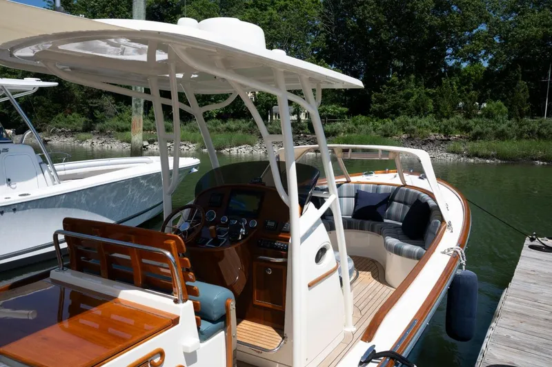 Slide: The Image of 2021 Hinckley Talaria 29C boat docked, featuring elegant wood finishes and spacious seating. - 5