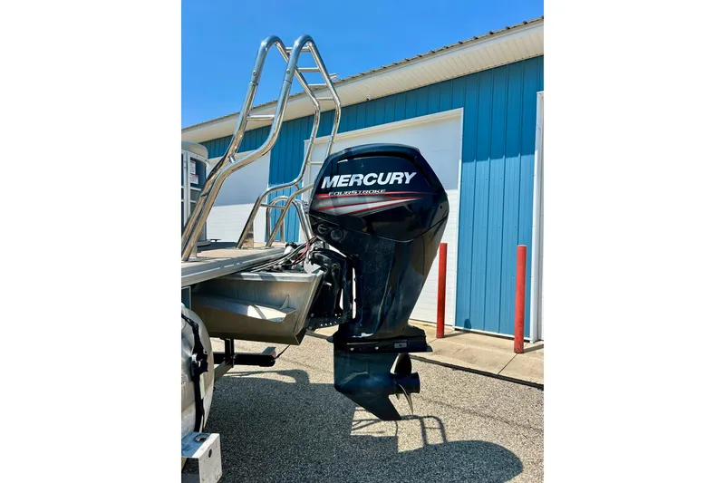 Slide: The Image of 2017 Starcraft CX 23 RE boat with Mercury outboard motor, parked near blue building. - 31