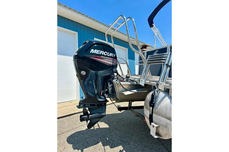 Slide: The Image of 2017 Starcraft CX 23 RE pontoon boat with Mercury outboard motor, parked near a blue building. - 7