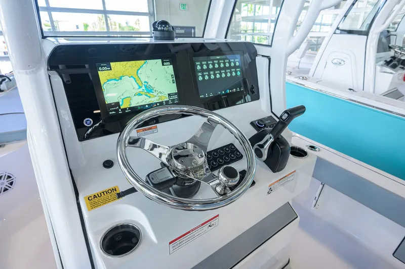 Slide: The Image of 2027 Sportsman Masters 227 Bay Boat dashboard with navigation screens and steering wheel. - 9