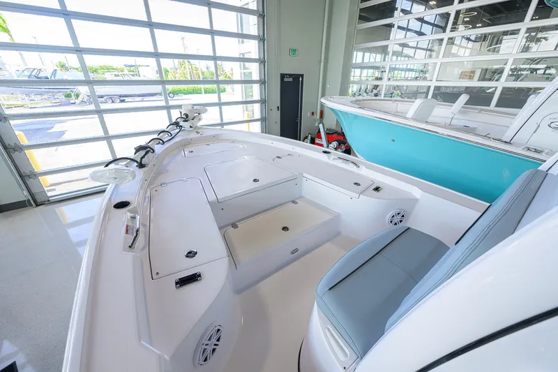 Slide: The Image of 2027 Sportsman Masters 227 Bay Boat interior with seating and storage, displayed in a showroom. - 15