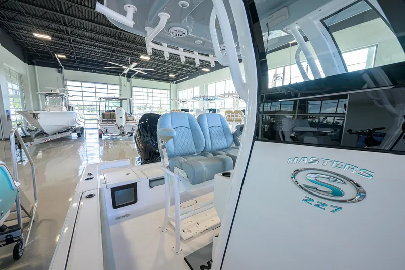Slide: The Image of 2027 Sportsman Masters 227 Bay Boat in showroom, featuring sleek design and modern seating. - 26
