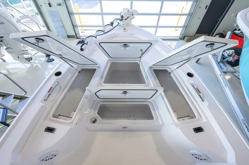 Slide: The Image of 2027 Sportsman Masters 227 Bay Boat with open storage compartments in a showroom. - 18