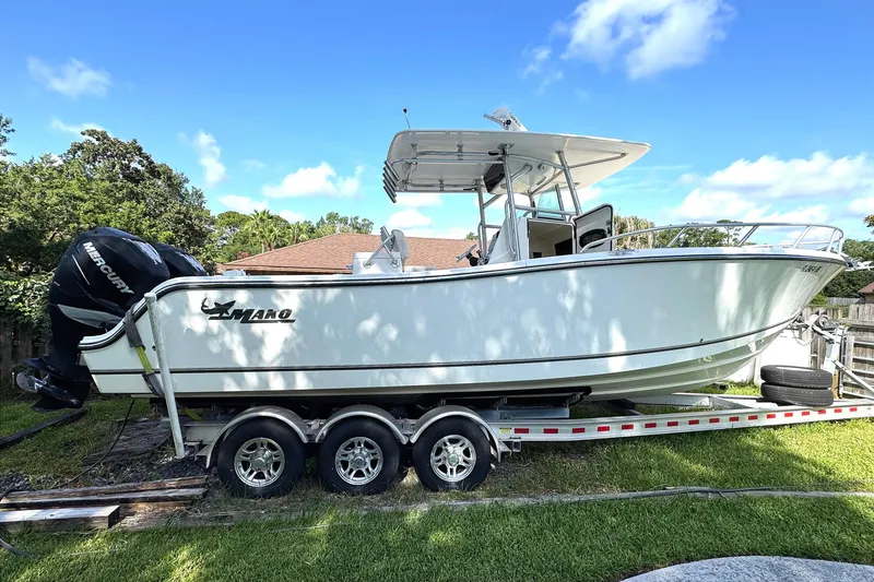 The Image of 2014 Mako 284 Center Console boat on trailer, parked on grass under blue sky. - 0