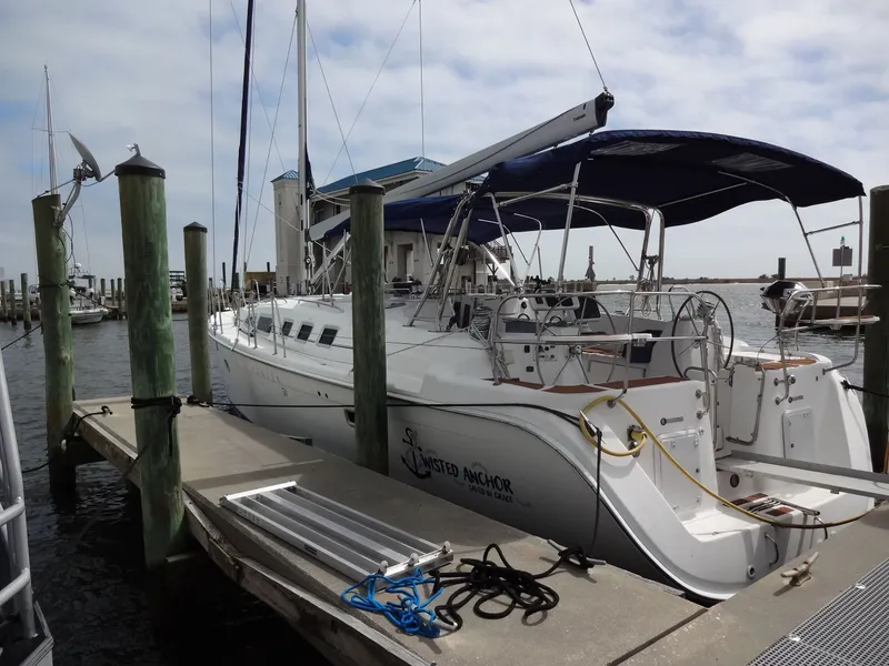 Slide: The Image of A 2009 Hunter 50 sailboat docked, featuring a blue sunshade and spacious aft deck. - 2