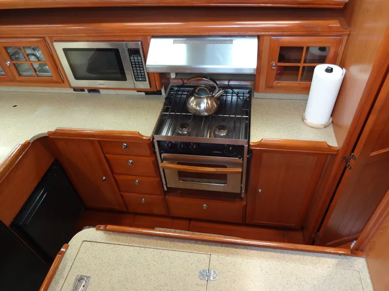 Slide: The Image of The galley of a 2009 Hunter 50 with a stove, microwave, and wooden cabinets. - 32