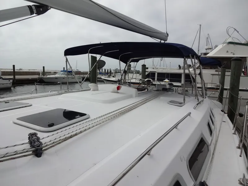 Slide: The Image of A 2009 Hunter 50 sailboat docked in a marina. It features a blue sunshade and spacious deck. - 24