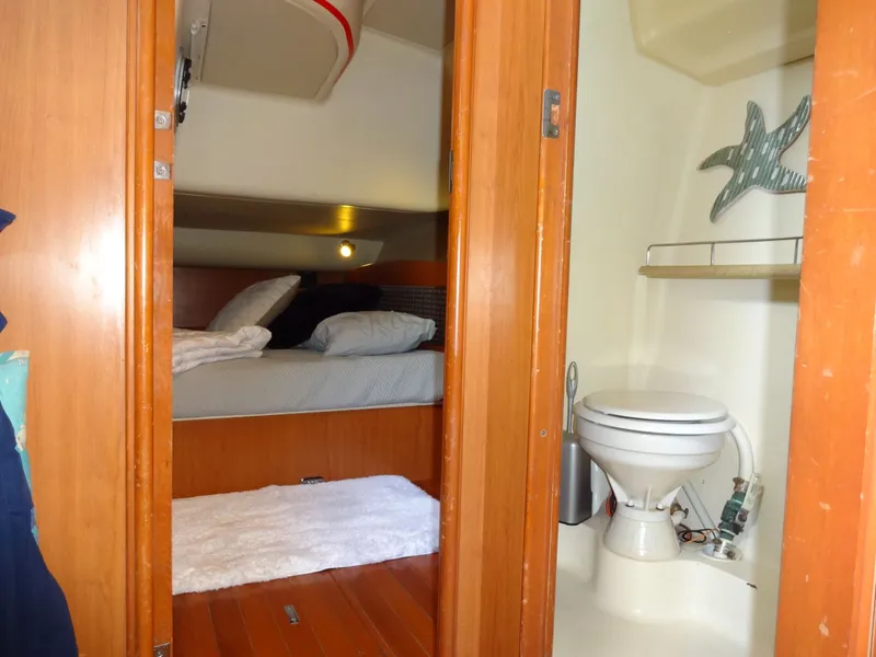 Slide: The Image of The cabin of a 2009 Hunter 50 features a cozy bed and an adjacent bathroom with a toilet. - 37