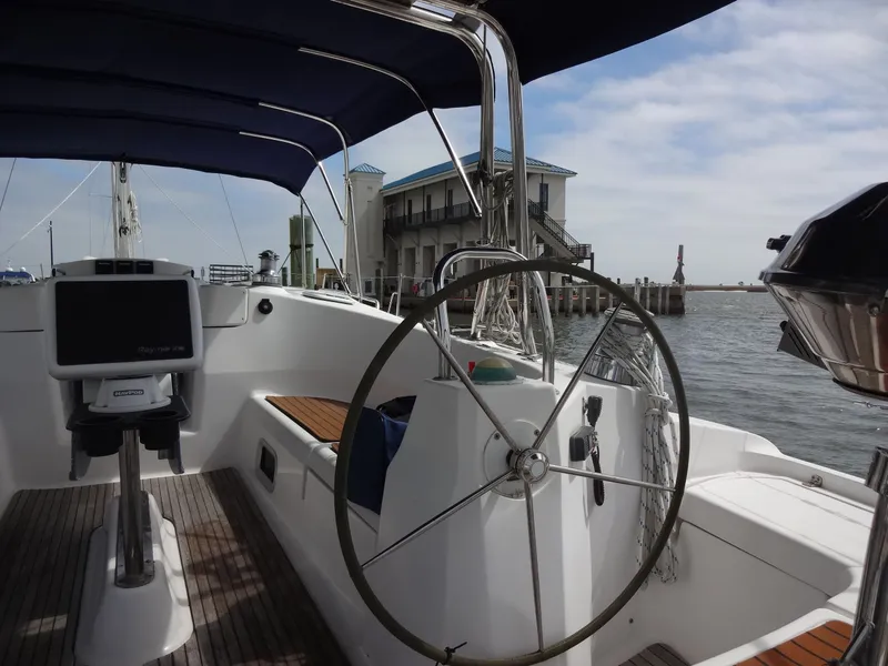Slide: The Image of The image shows the cockpit of a 2009 Hunter 50. It features a large steering wheel and modern navigation console. A waterfront building is visible in the background. - 8