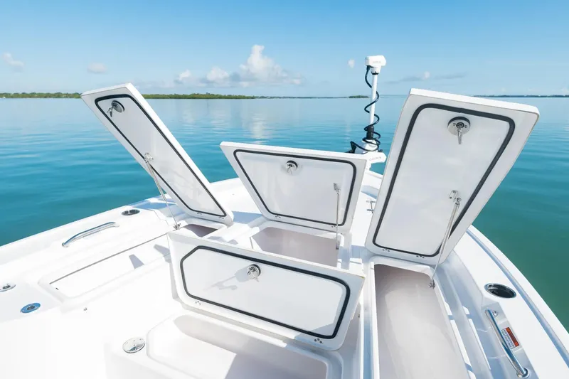 Slide: The Image of 2026 Sportsman Masters 247 Bay Boat with open storage compartments on calm water. - 5